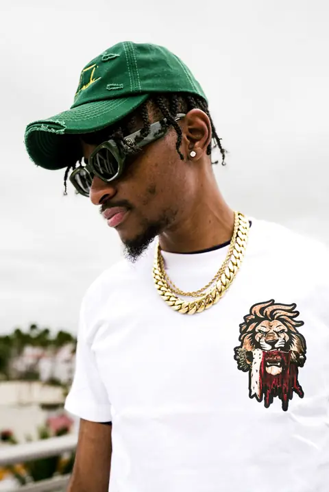 White heavyweight tee with the crowned LDI lion print, worn with a green signature cap